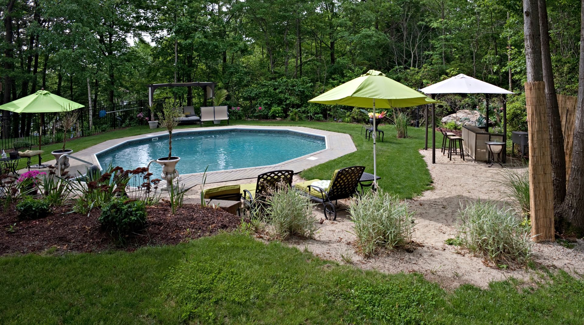 A backyard with a pool and seating, a mosquito misting system is installed around the yard